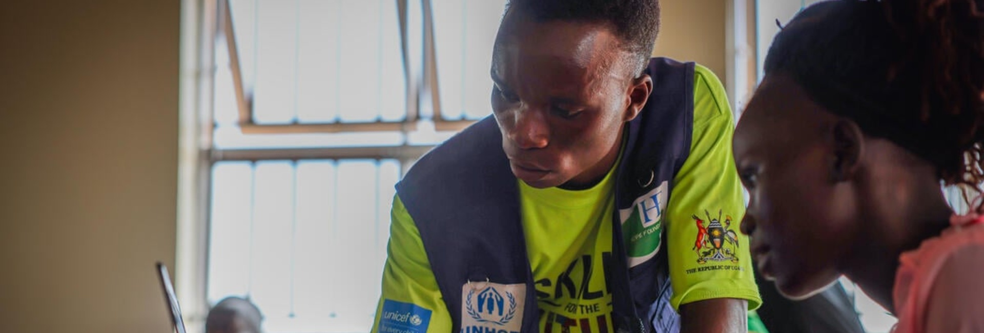 An instructor and a student looking at a computer at a community centre in Uganda.