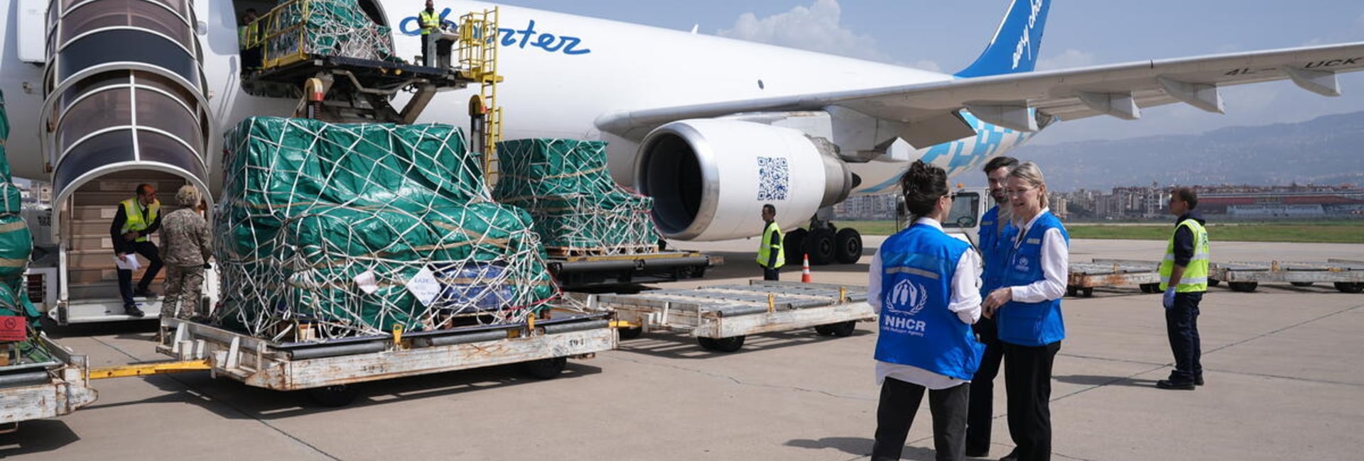 UNHCR staff stand beside a plane delivering supplies.