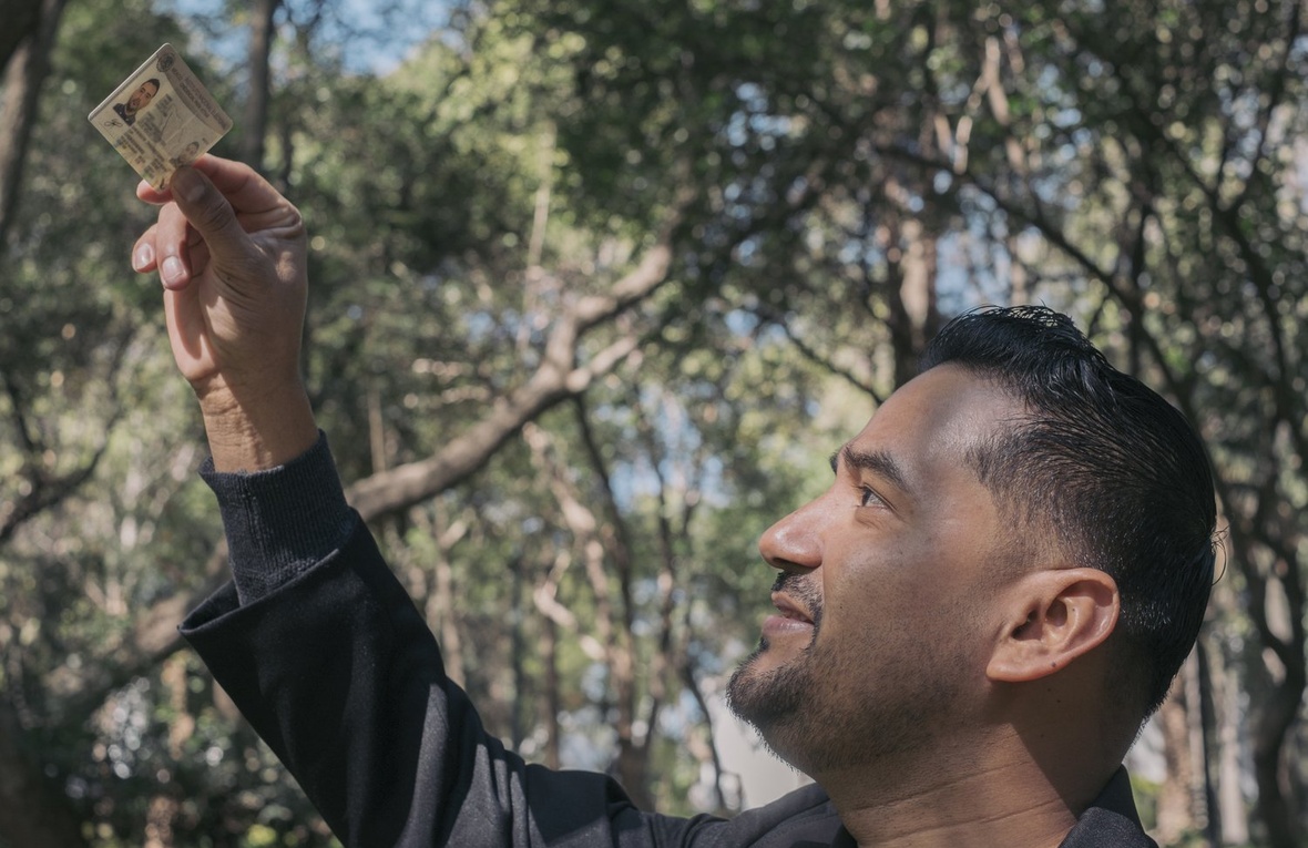 A man looks at an ID he is holding up.
