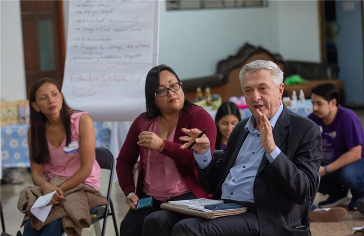 Two women and a man are talking while sitting in a room during a public event.