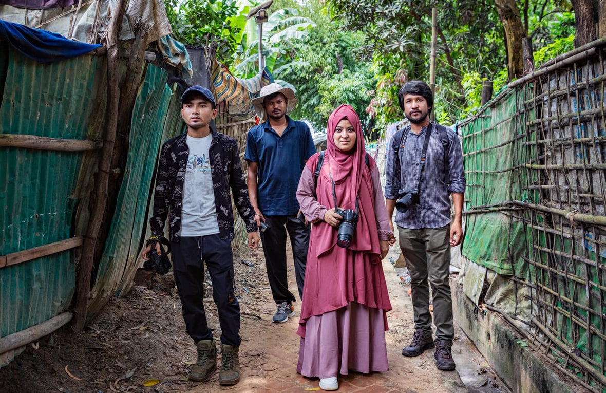 Four photographers pose for a photo in the jungle, between two fences