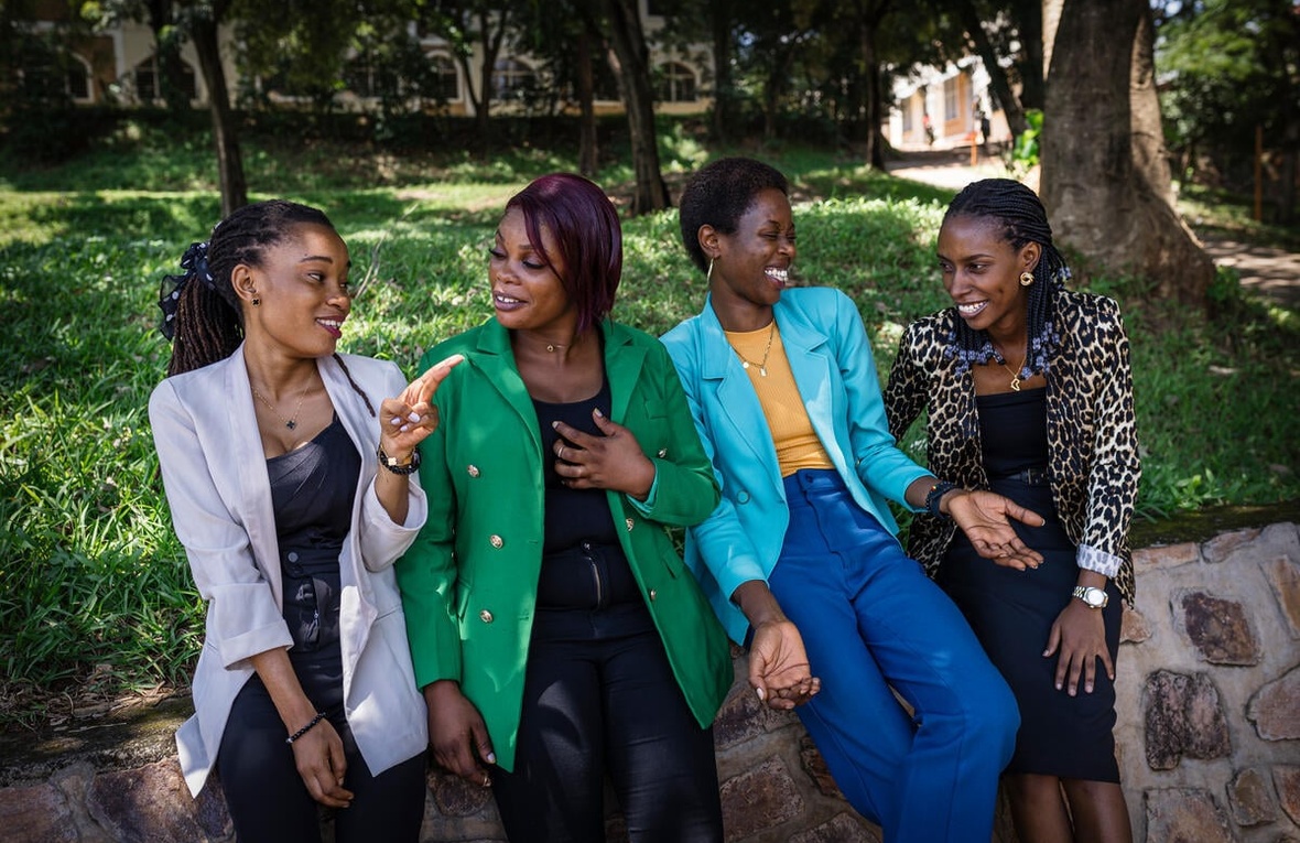 Four women sit together in a park and talk with each other.