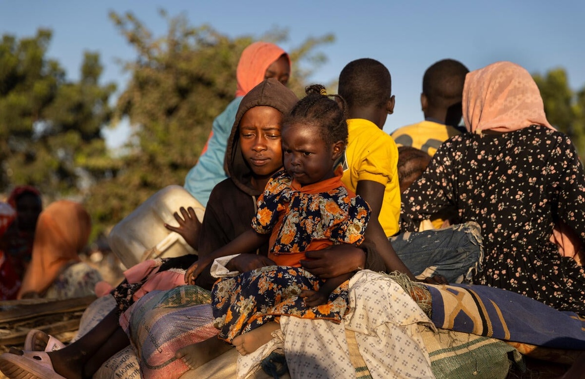 Families gather outside with their belongings.