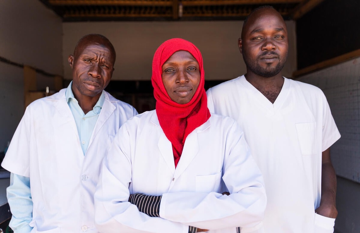 Three medical staff look at the camera, looking serious. 