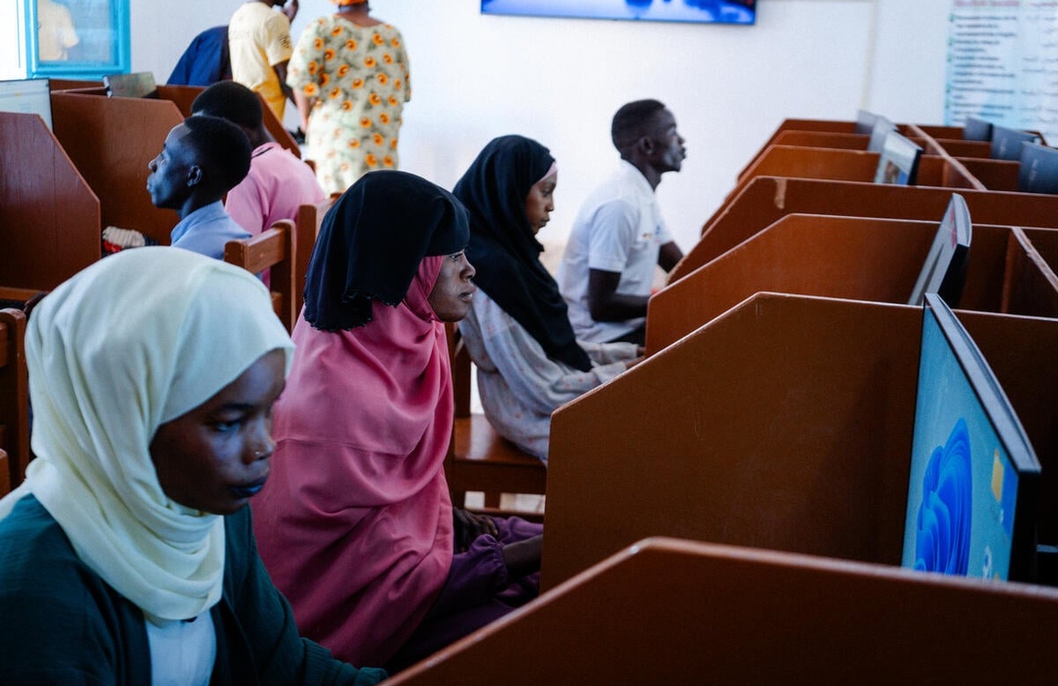 Sudanese refugees sit at computers in cubicles