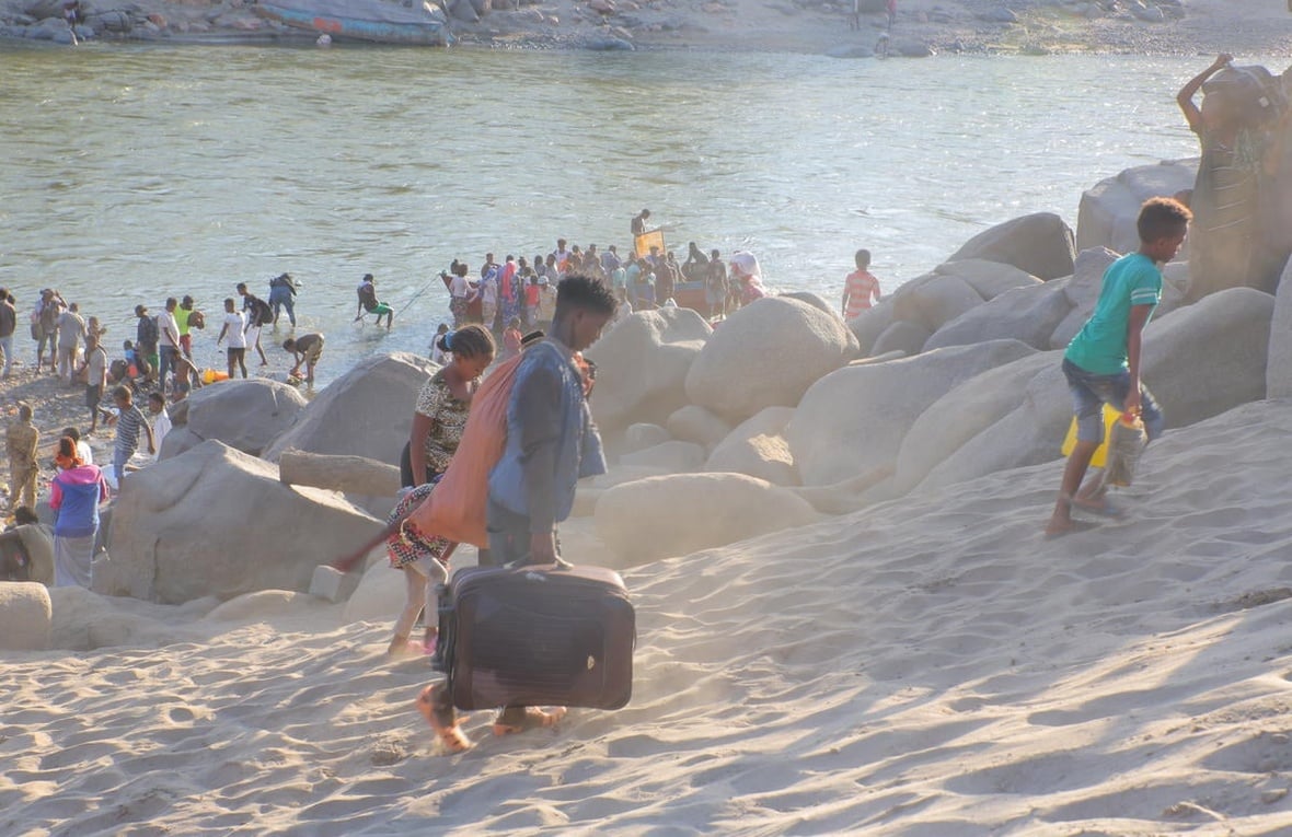 Ethiopian refugees flee across a river with their belongings.