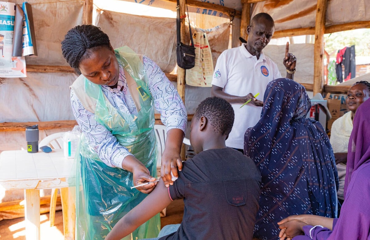 Several people receive vaccinations and other medical consultation in a makeshift shelter outdoors