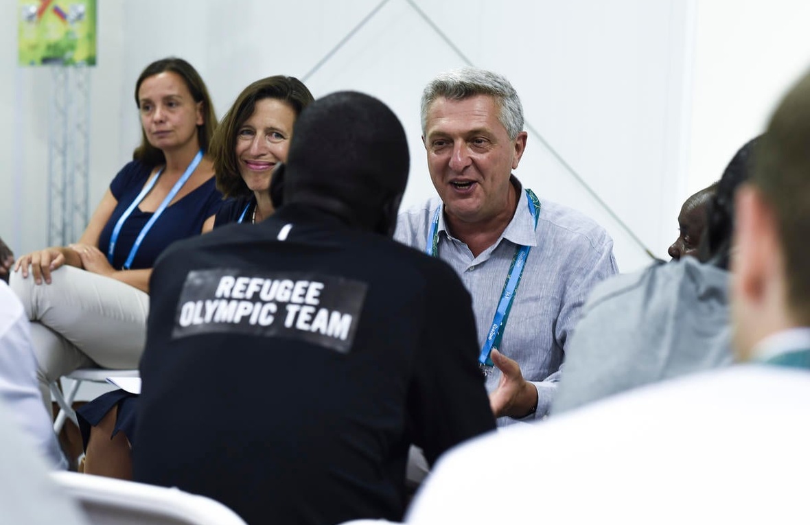 UN High Commissioner for Refugees Filippo Grandi chatting with a person with 'Refugee Olympic Team' on the back of their jumper