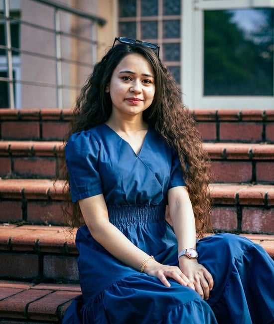 Roshin sits outside on stairs at the university campus