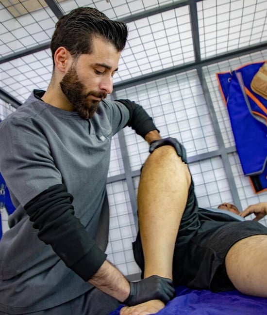 Fawaz holds the knee and ankle of a patient during a physiotherapy session