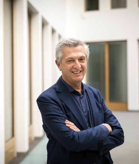 UN High Commissioner for Refugees, Filippo Grandi, stands smiling with his arms crossed.
