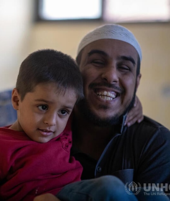 A man holding his son and smiling at the camera.