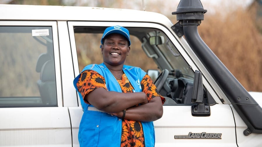  Rose, a UNHCR driver, smiles for the camera as she stands in front of the Landcruiser she drives.