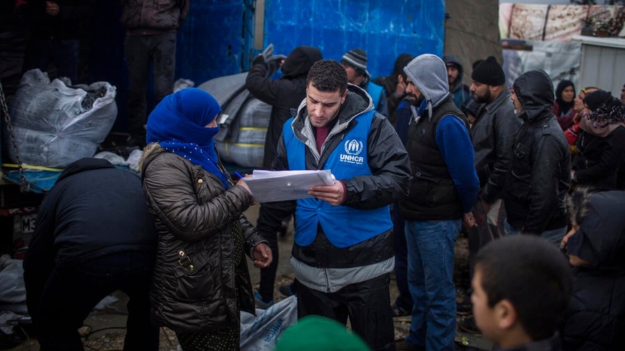 A UNHCR staff member speaks with a Syrian refugee woman in Lebanon