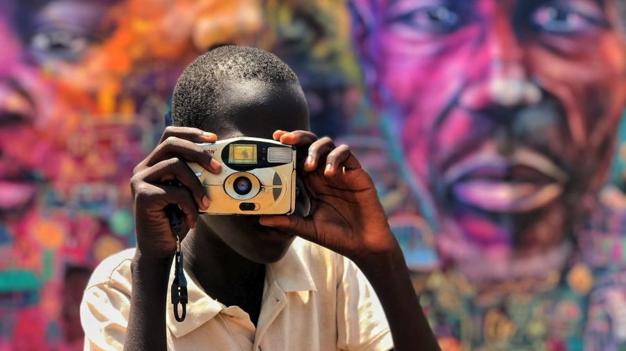South Sudanese refugee takes a photo with a digital camera
