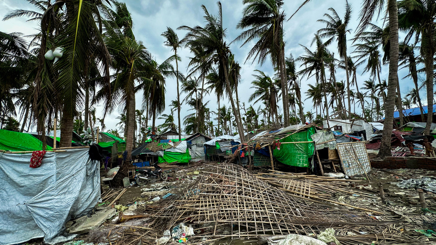 Makeshift shelters covered in tarpaulin dot a landscape littered with debris following a storm.