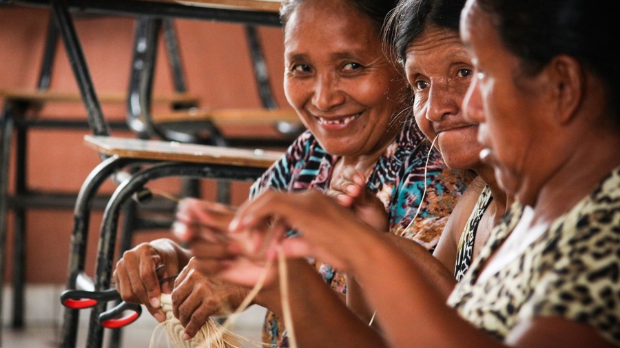 Three old women sit next to each other and craft.