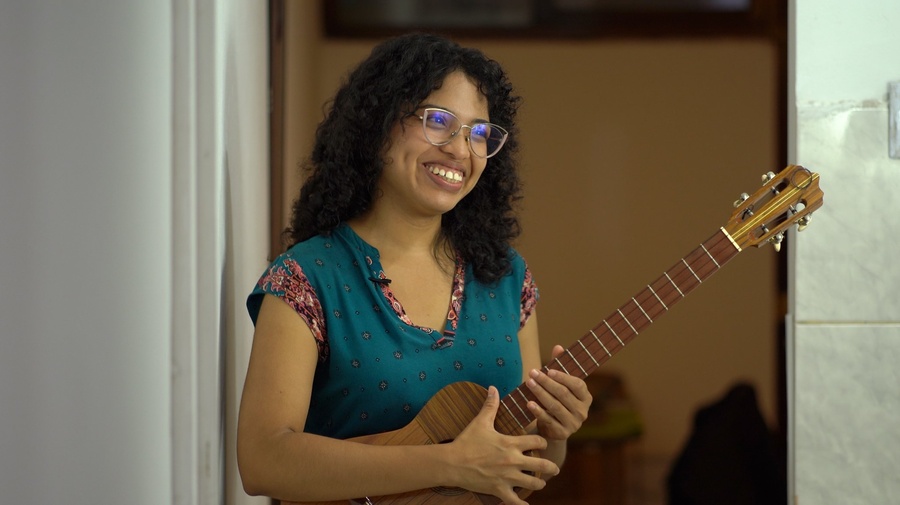 A young woman smiling and playing the guitar