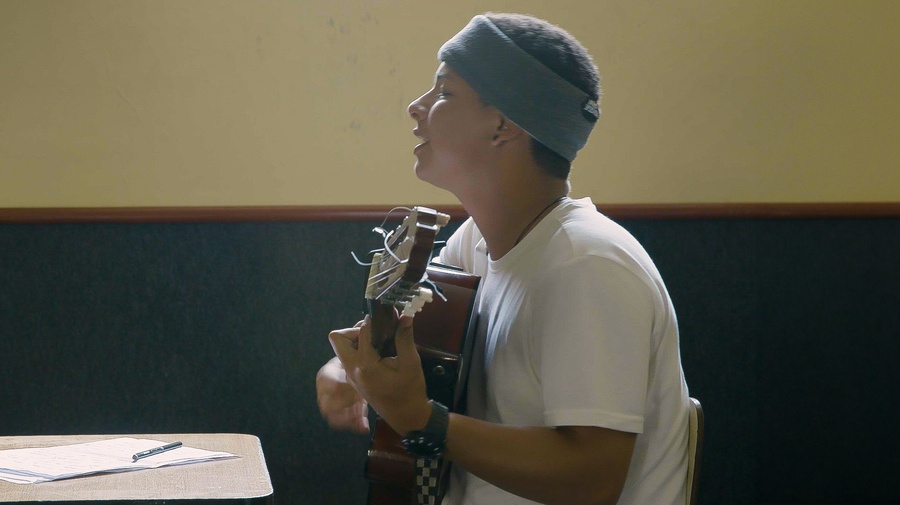 A young man playing the guitar while singing