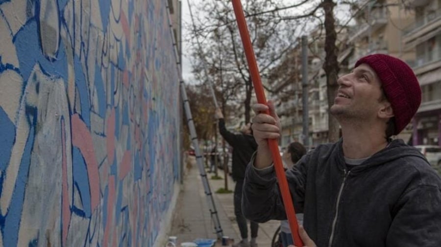 A man creates a mural on a wall.