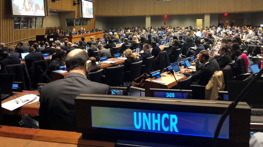 A conference room full of people with large screens at the front.