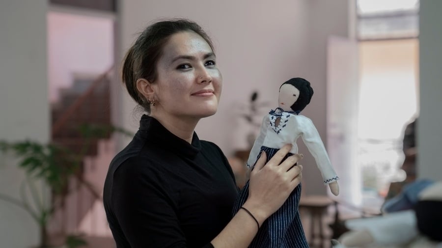 India. Afghan refugee with a doll she sewed as part of an enterprise that reworks the waste of the fast fashion industry. 