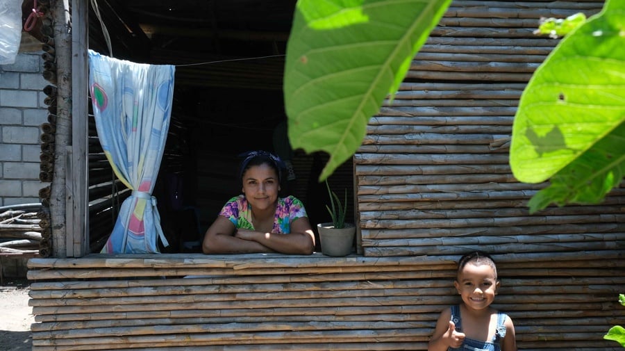 Rosmary Yaure, a Venezuelan returnee, smiles while holding her young son Leon outside their home in San Cristobal. After spending time in several Colombian cities working as a snack vendor, she returned to Venezuela a year ago.