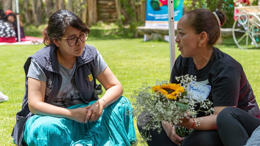 María Luisa Mamani Salamanca, a Bolivian activist, sits in a community space engaging with refugee and migrant women as part of her work supporting survivors of gender-based violence