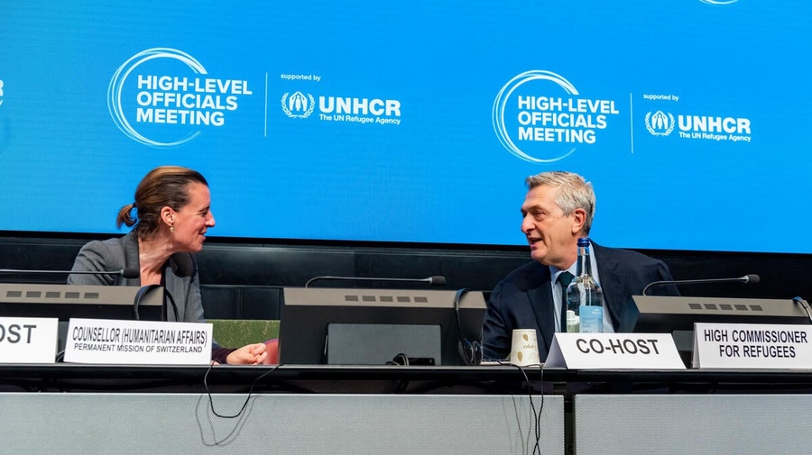 A woman and a man face each other at the podium.