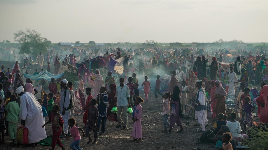 A large number of new arrivals from Sudan wait in a field in South Sudan