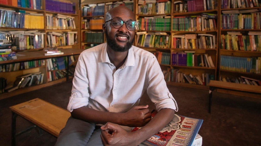 Abdullahi Mire sits smiling in a library