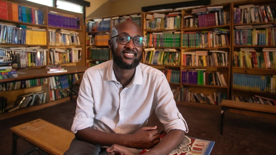 Abdullahi Mire sits smiling in a library