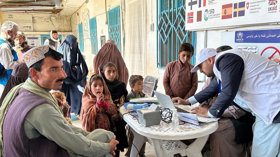 An Afghan refugee man and his young family have their details registered on a computer. 