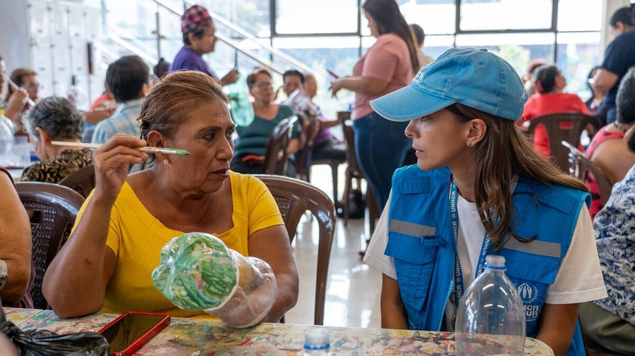 A UNHCR staff member talks with an older woman during an art class in El Salvador.