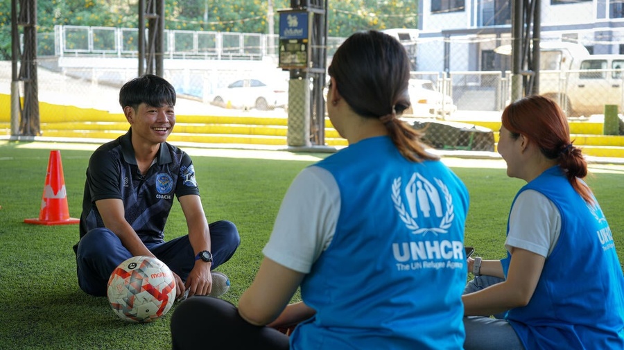Thailand. Arso, 25, a stateless person, sits and chats with UNHCR staff at the football school where he volunteers