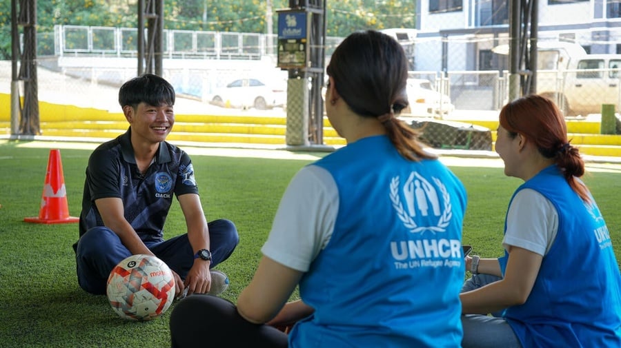 Thailand. Arso, 25, a stateless person, sits and chats with UNHCR staff at the football school where he volunteers
