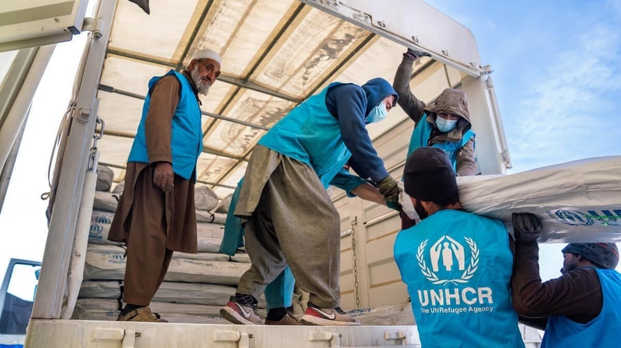 UNHCR staff work together to load supplies into a truck
