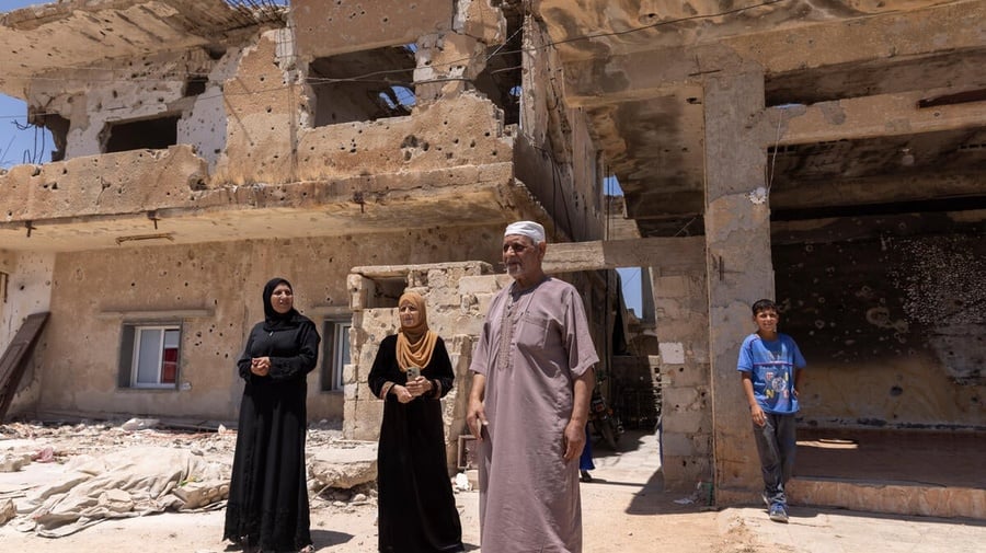 A family of four refugee returnees stand in front of a partially-collapsed building – their home in Daraa, southern Syria