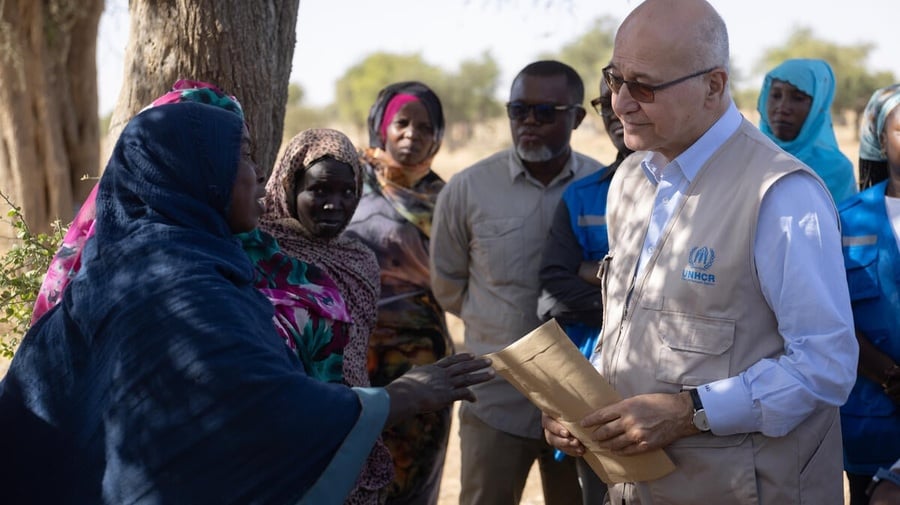 Barham Salih speaks to refugees and community members outside beside a large tree