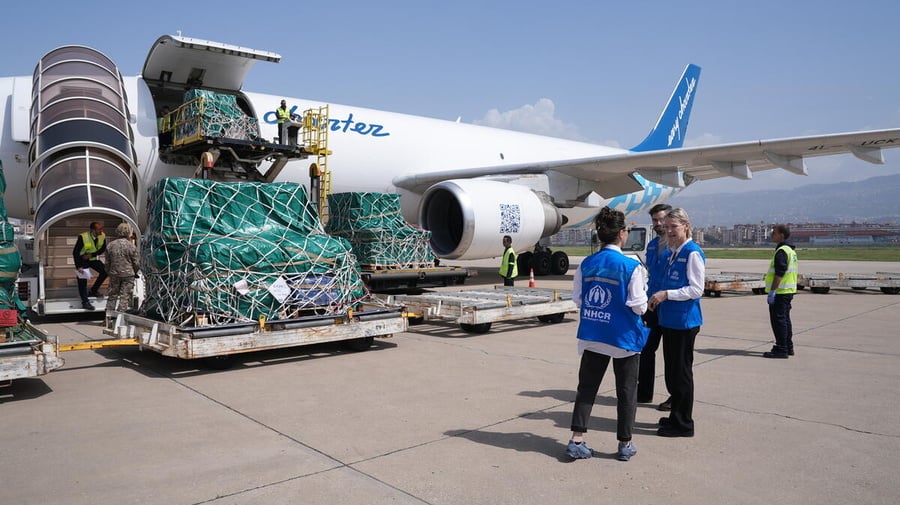 UNHCR staff stand beside a plane delivering supplies.