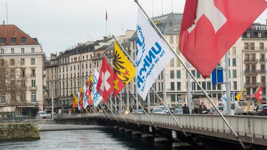 UNHCR’s flag flies alongside the Swiss flag on a bridge over a river. 