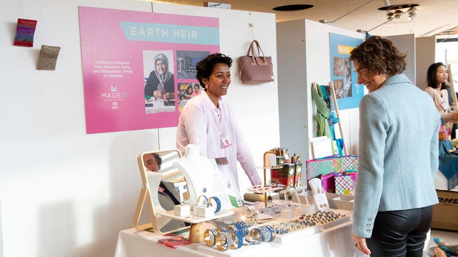 A woman browses jewelry and handicrafts at an indoor market stall.