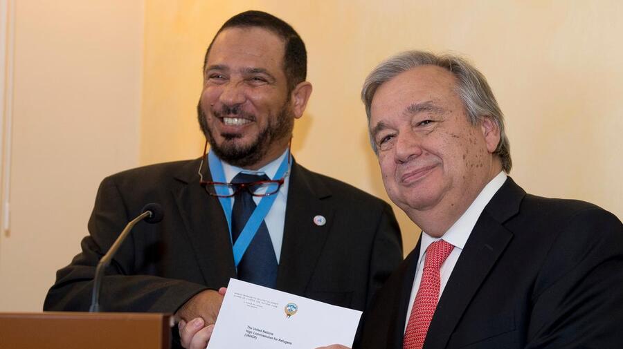 António Guterres, the UN High Commissioner for Refugees, holds the cheque he has just received from Abdullah Al-Matouq, advisor to the Emir of Kuwait.