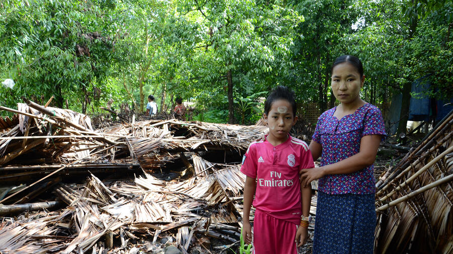 Ma Nge and her 10-year-old son stand outside the remains of their home in a small village in Ponnagyun township, Rakhine State.