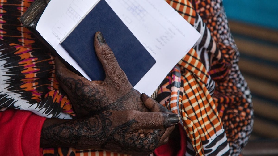 Folded hands hold blue and white document papers.