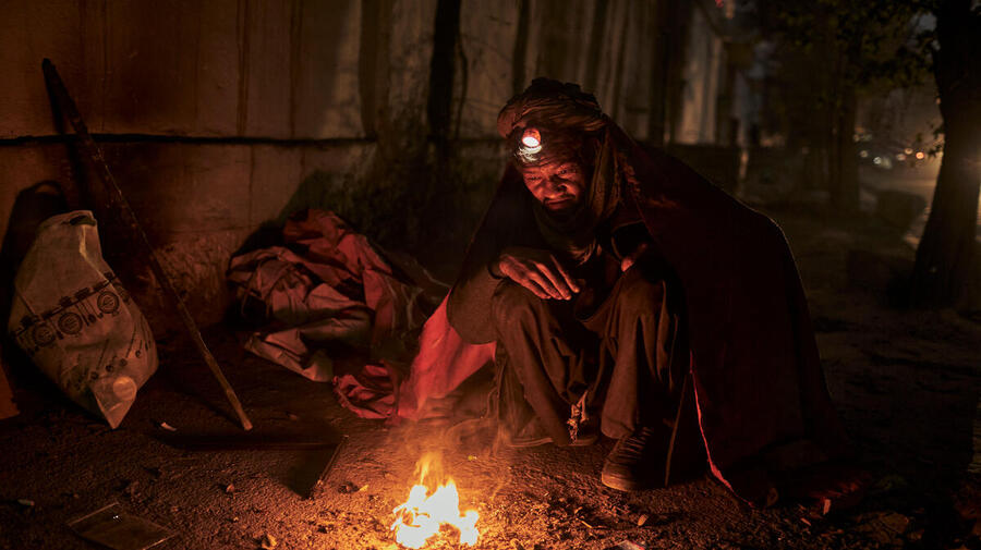 A homeless man seeks warmth from a small fire on the streets of Kabul, Afghanistan, as winter draws in.