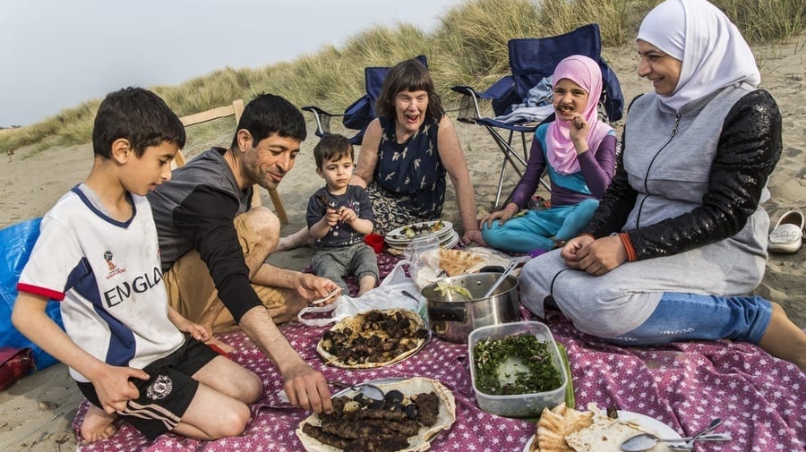 A group of adults and children eating a picnic lunch