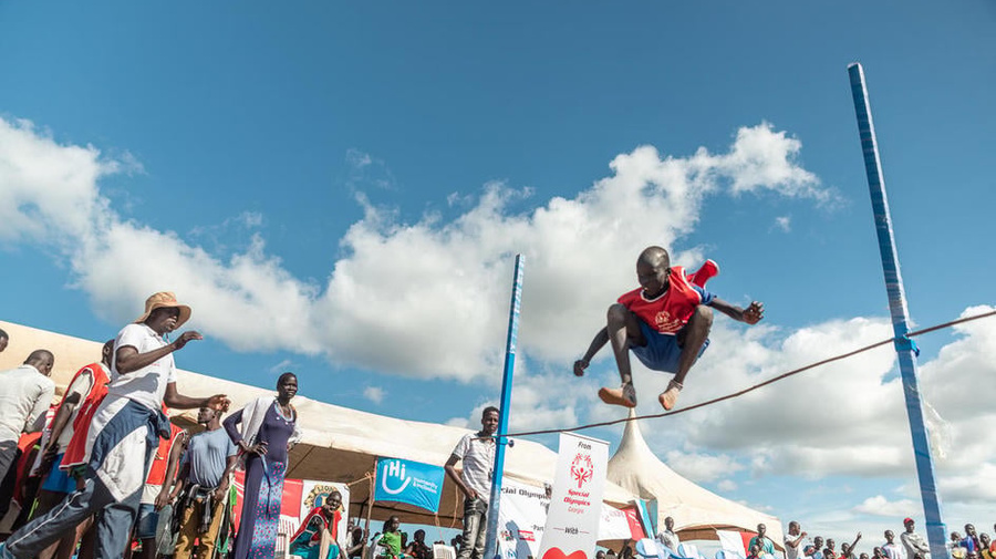 A young boy jumping over a hedge